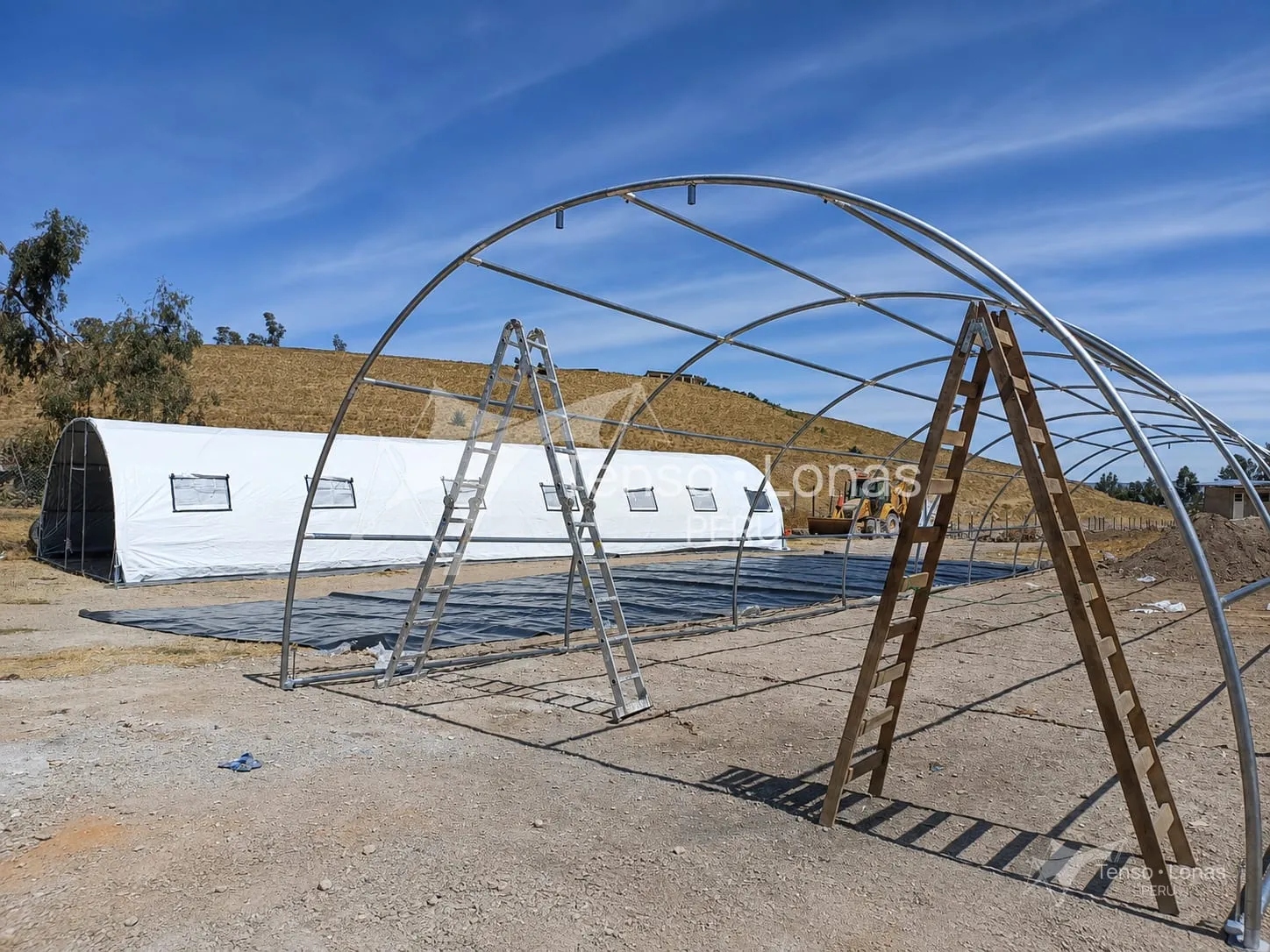 Estructura metálica curva de una carpa industrial durante el montaje