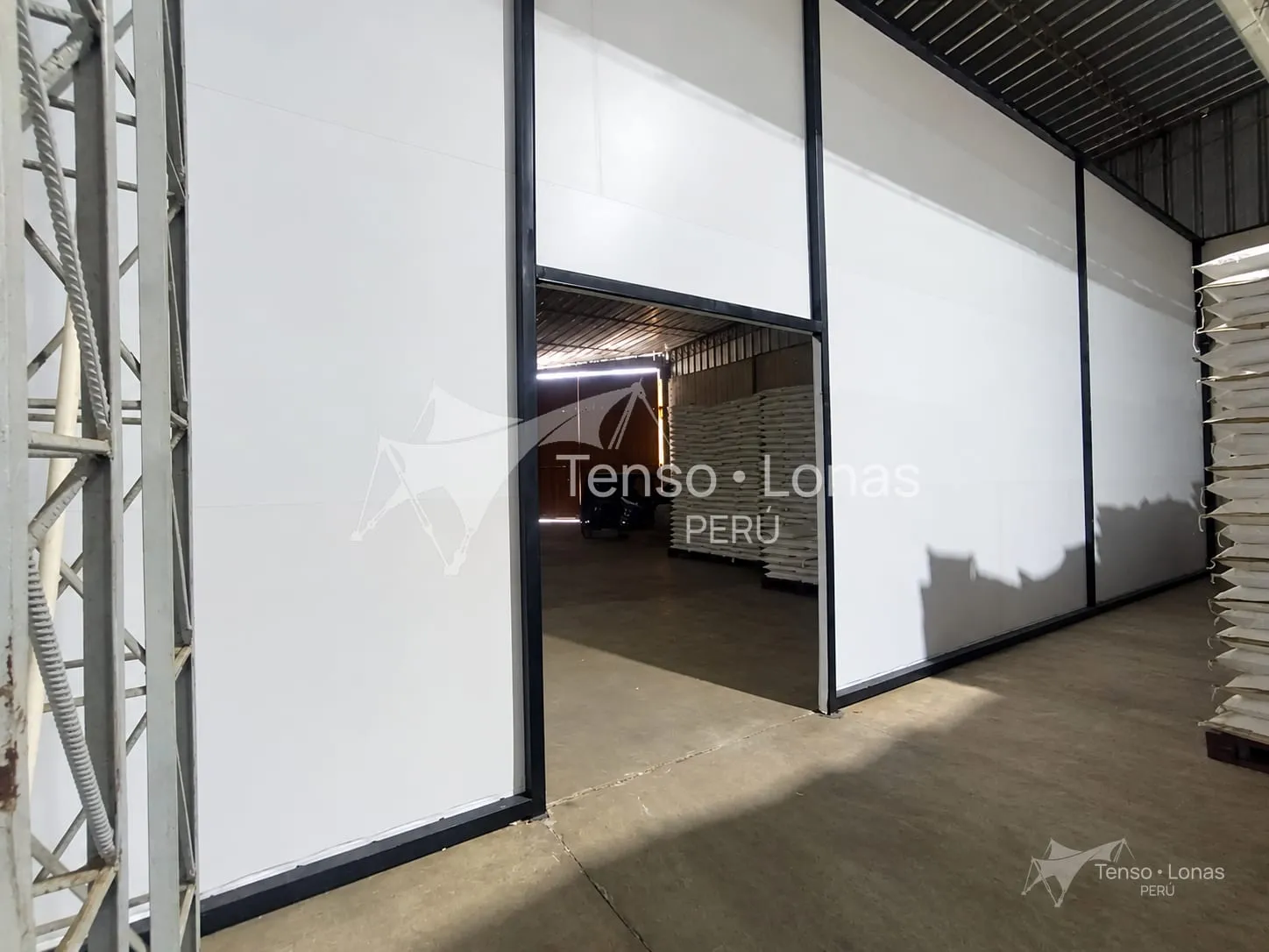 Interior de un almacén con paredes de lona PVC blanca y portón de acceso