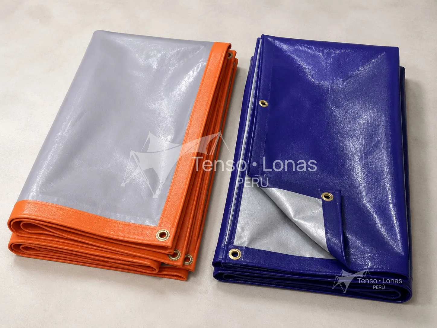 Dos mantas de tarflex plegadas, una gris con ribete naranja y otra azul con revés plateado, con ojales de bronce en el borde