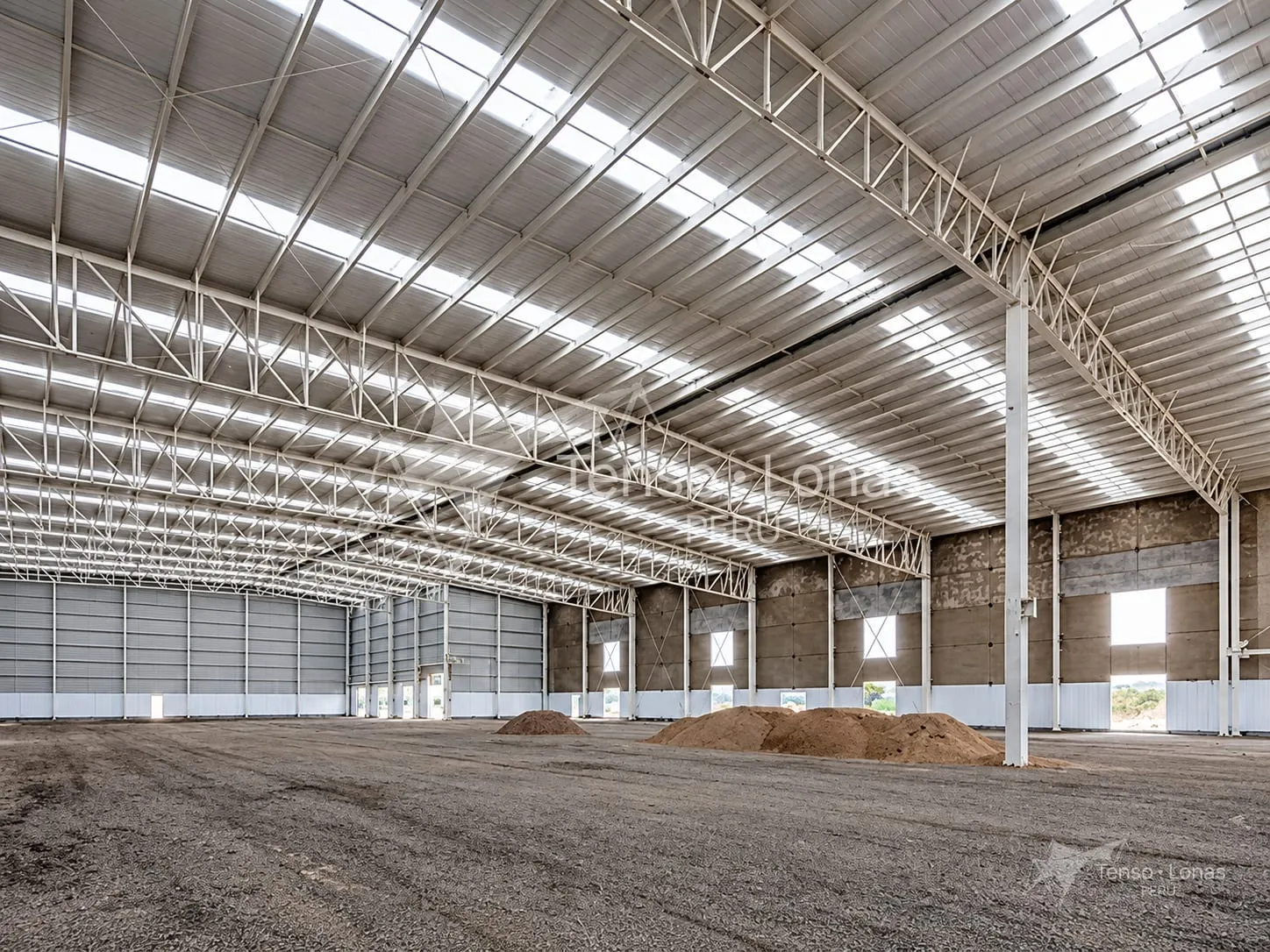Interior de una nave industrial con tijerales metálicos y gran altura libre