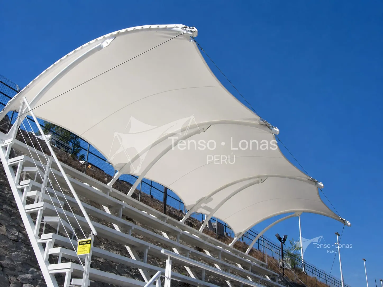 Toldo tensado blanco sobre las graderías de un área exterior